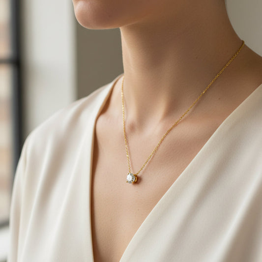 Gold necklace with a diamond pendant on a light gray background