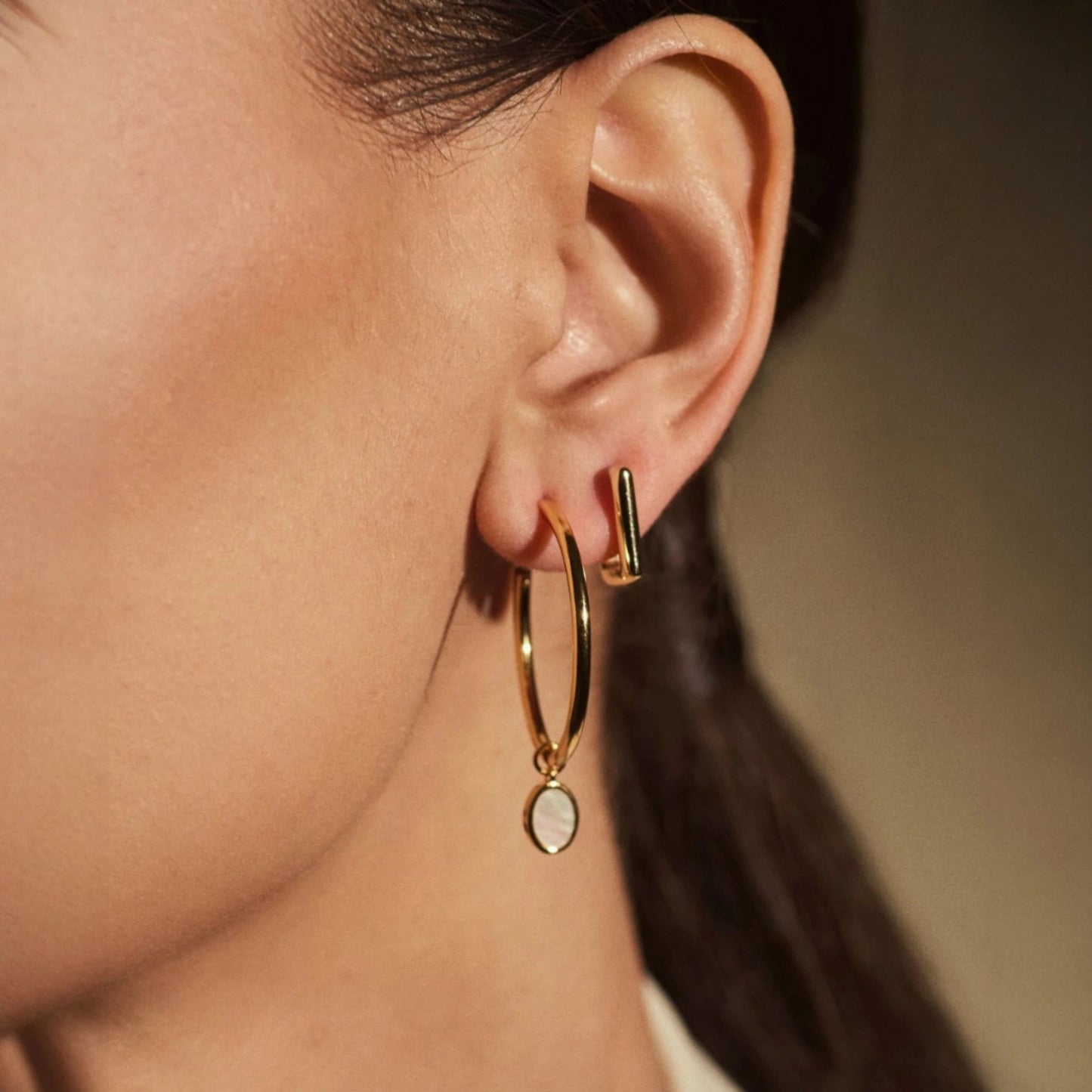 Woman wearing FYB Erin square gold huggie earrings