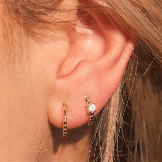 Woman wearing FYB Zia minimalist gold huggie earrings