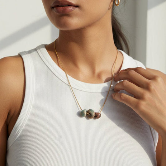 Necklace with three beads on a light gray background
