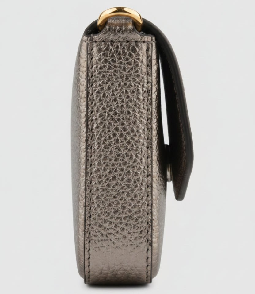 Close-up side view of a metallic taupe leather pouch or wallet with a pebbled texture and a black strap, shown on a plain white background.