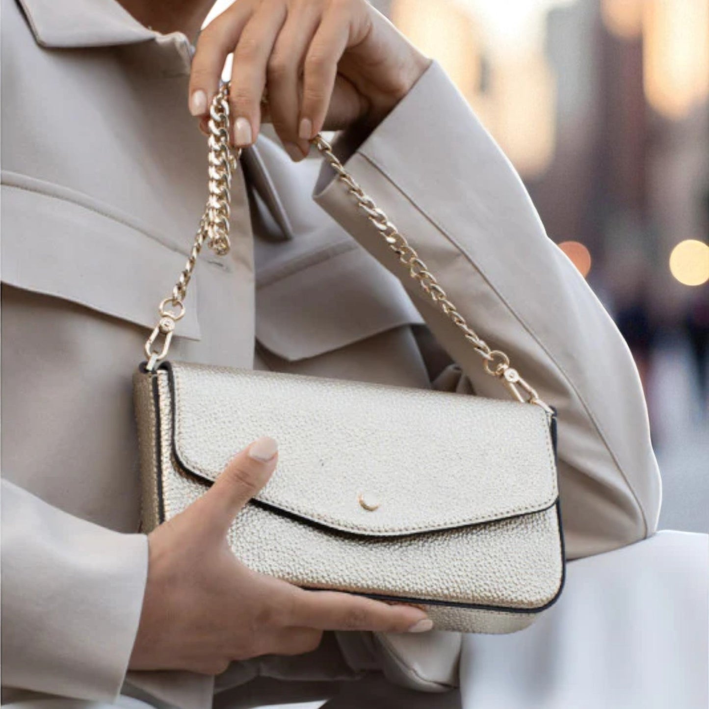 Pourchet club in gold color with gold chain held by a person wearing a beige coat.