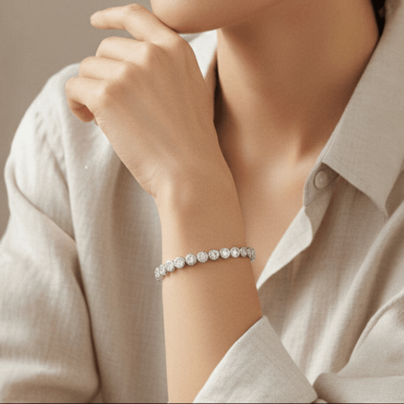 Woman's wrist with a tennis bracelet with stones set in round bezel in sterling silver