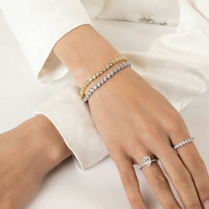 Close up of model hands wearing the CHOE gold and silver sterling silver tennis bracelets with round bezel setting 