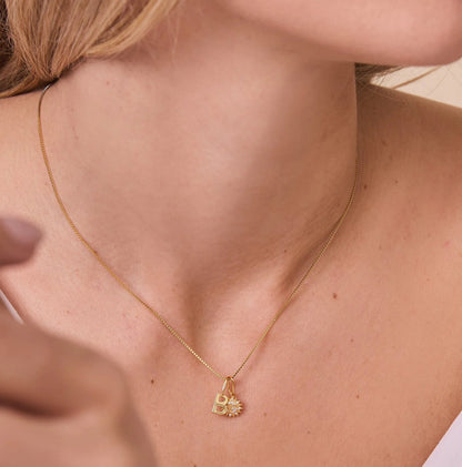 FYB charm necklace with initial and sun charm on a woman's neck