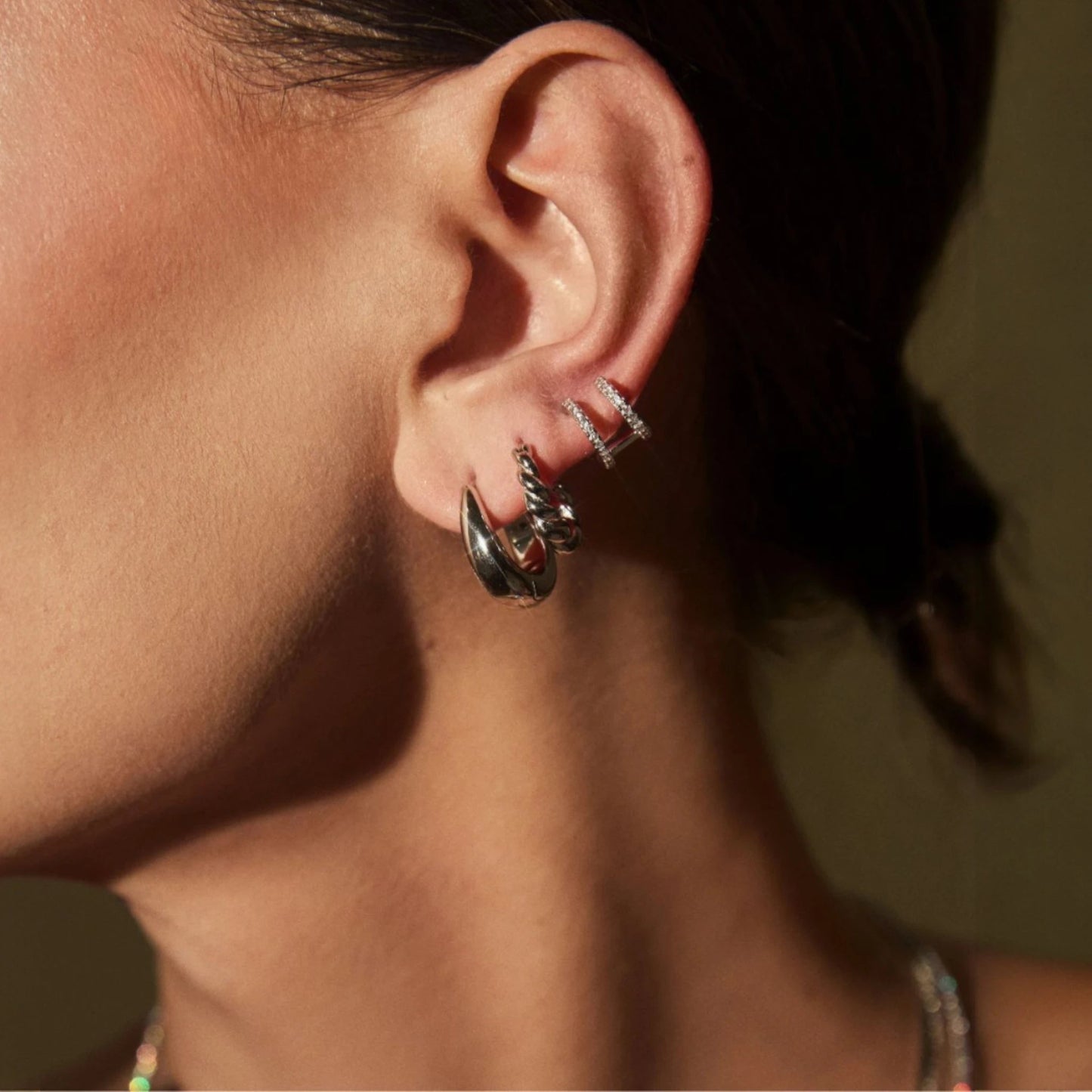 Close up of woman wearing FYB Delaney gold huggie earrings with pavé cubic zirconia stones
