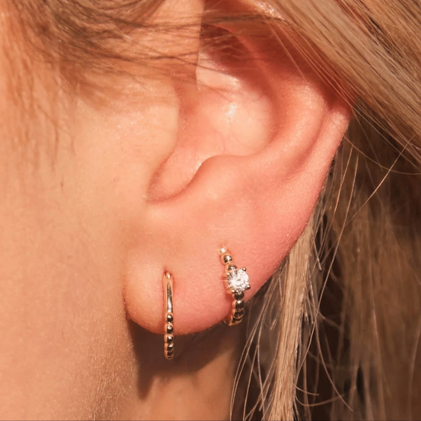 Woman wearing FYB Zia minimalist gold huggie earrings