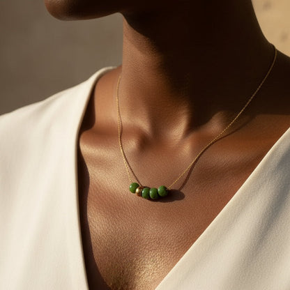 Necklace with green beads and a gold clasp on a white background