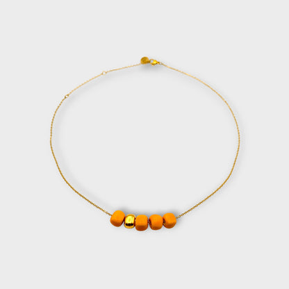 Maximilianas Cinco Cuentas necklace with four orange ceramic beads and one gold ceramic bead - product shot.