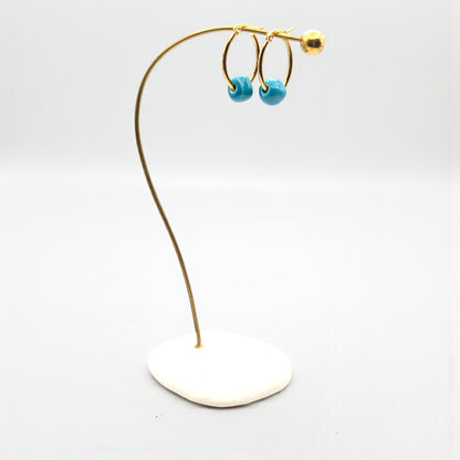 Maximilianas gold oval hoop earrings with removable turquoise bead on product stand