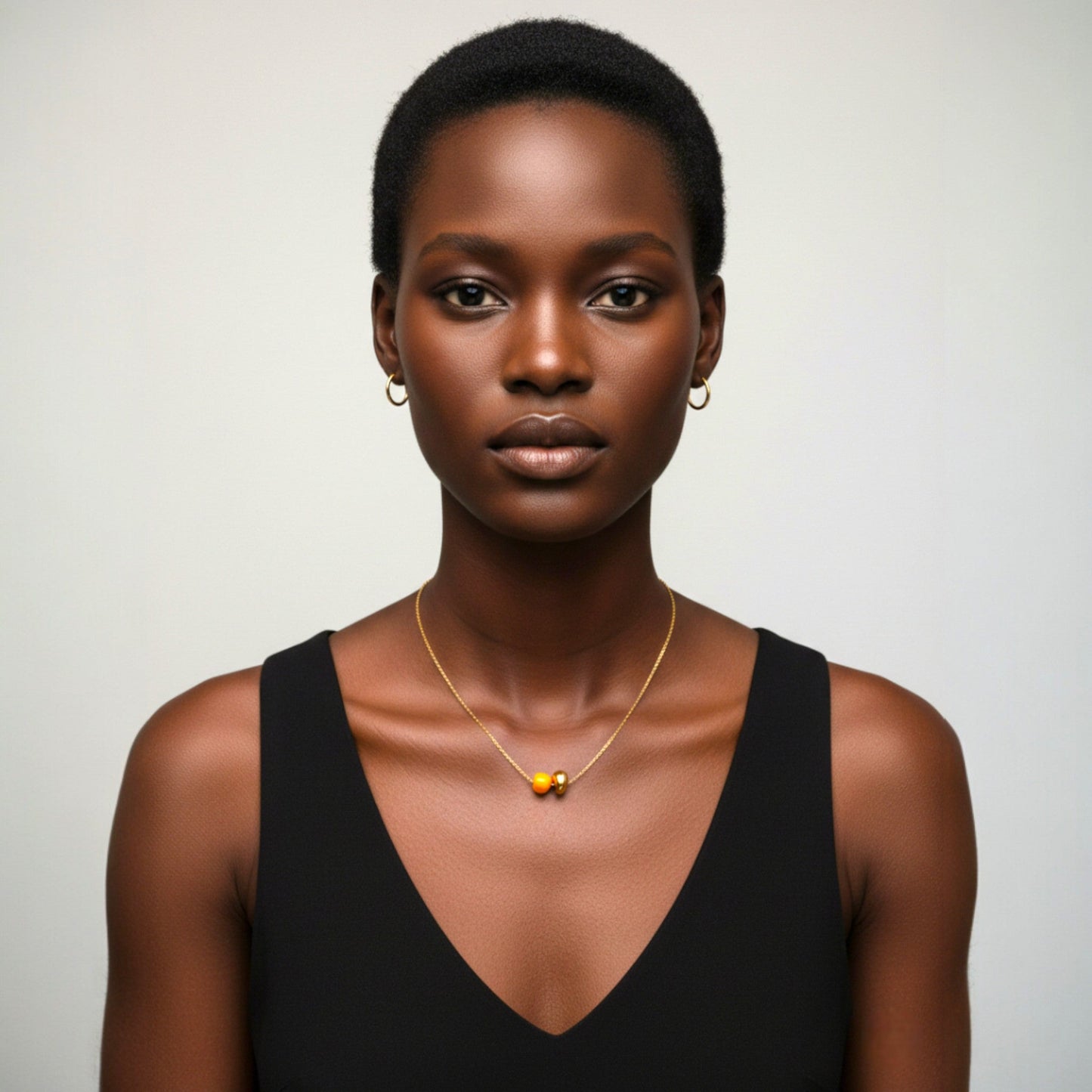 Woman wearing the Maximilianas Dos Cuentas necklace with one orange and one gold ceramic bead