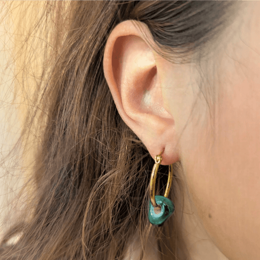 Close up shot of Maximilianas oval hoop earrings with green bead 