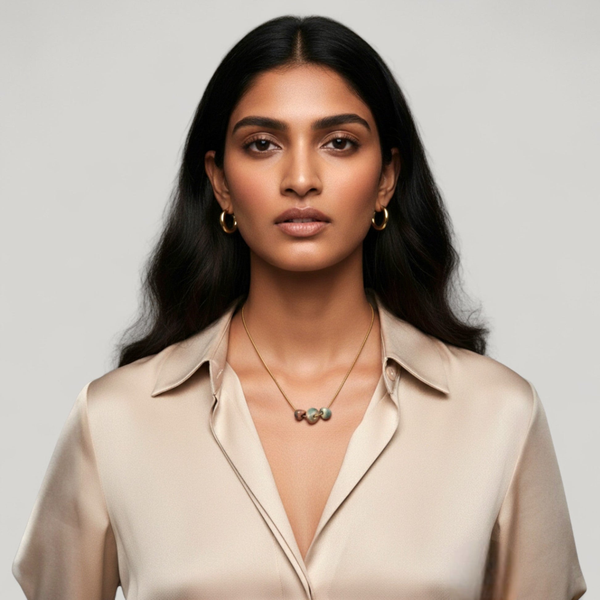Woman wearing Maximilianas Tres Petras necklace with three forest green ceramic beads - hero shot.