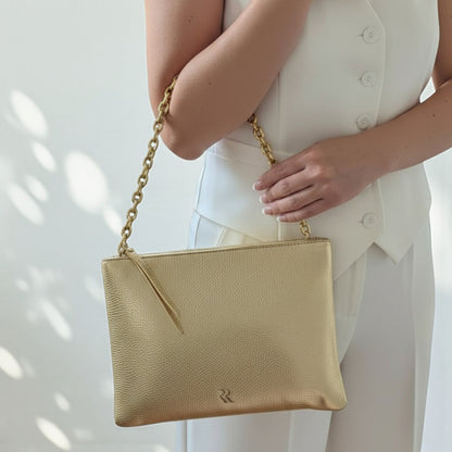 Rossi gold calf leather pouch - front view with chain strap held by a person wearing a white outfit.