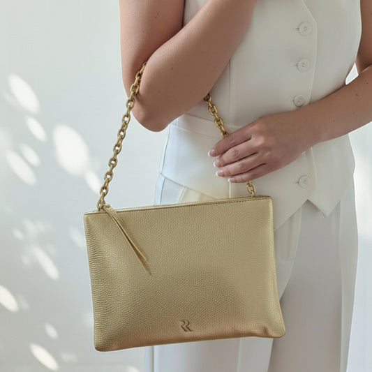 Rossi gold calf leather pouch - front view with chain strap held by a person wearing a white outfit.