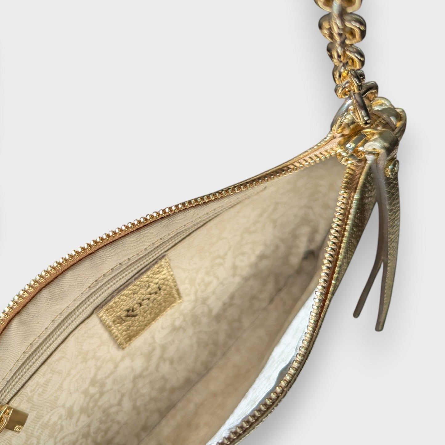 Rossi gold pouch with close-up of beige interior, open gold zipper and chain shoulder strap on a white background